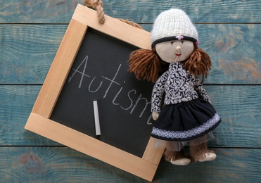 Photo of Chalkboard with word "Autism" and doll on wooden background