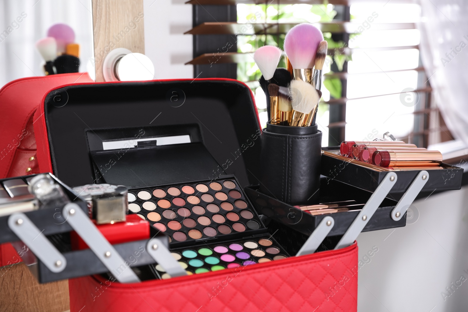 Photo of Beautician case with professional makeup products and tools on dressing table