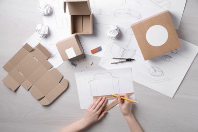 Photo of Woman creating packaging design at light wooden table, top view