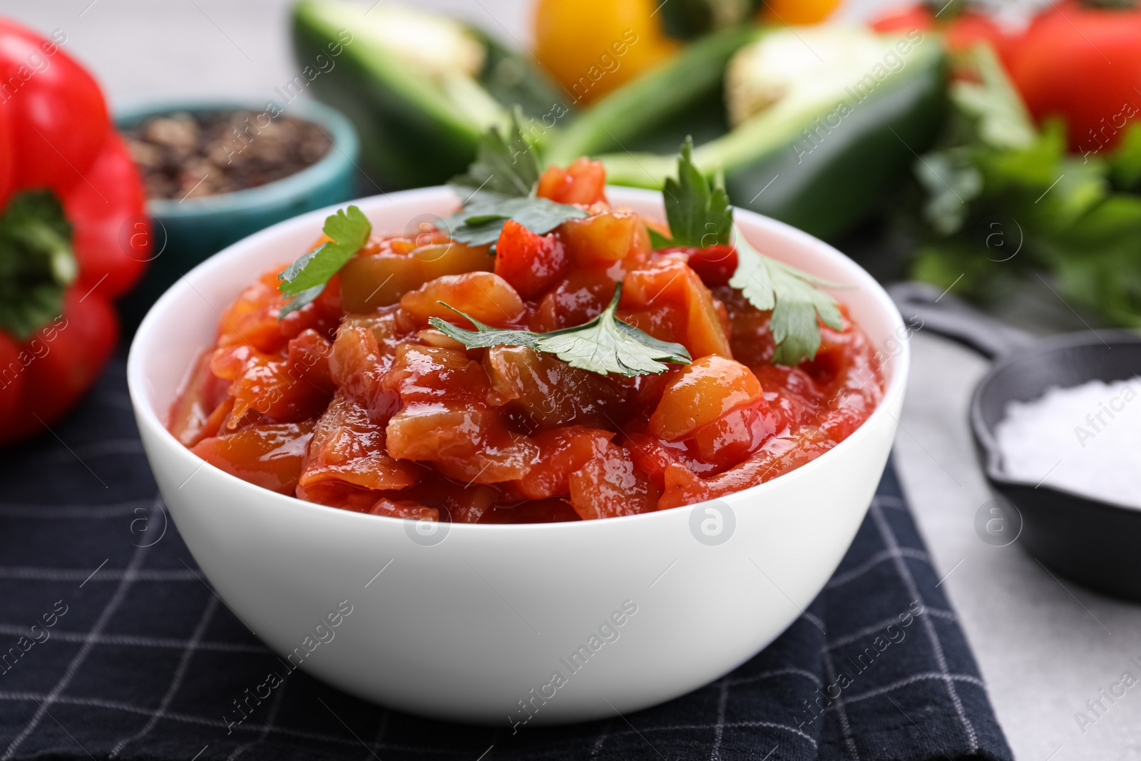 Photo of Delicious lecho with parsley in bowl on table, closeup