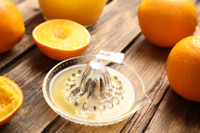 Fresh ripe oranges and squeezer on wooden table, closeup