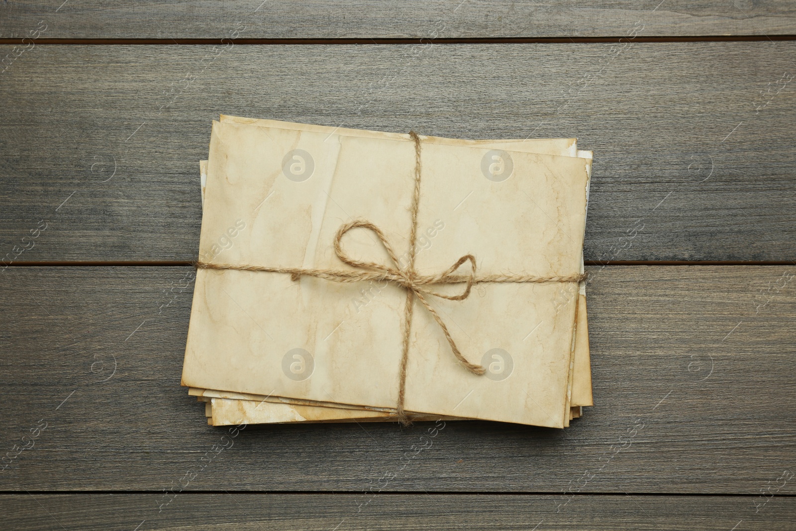 Photo of Stack of old letters tied with twine on wooden table, top view