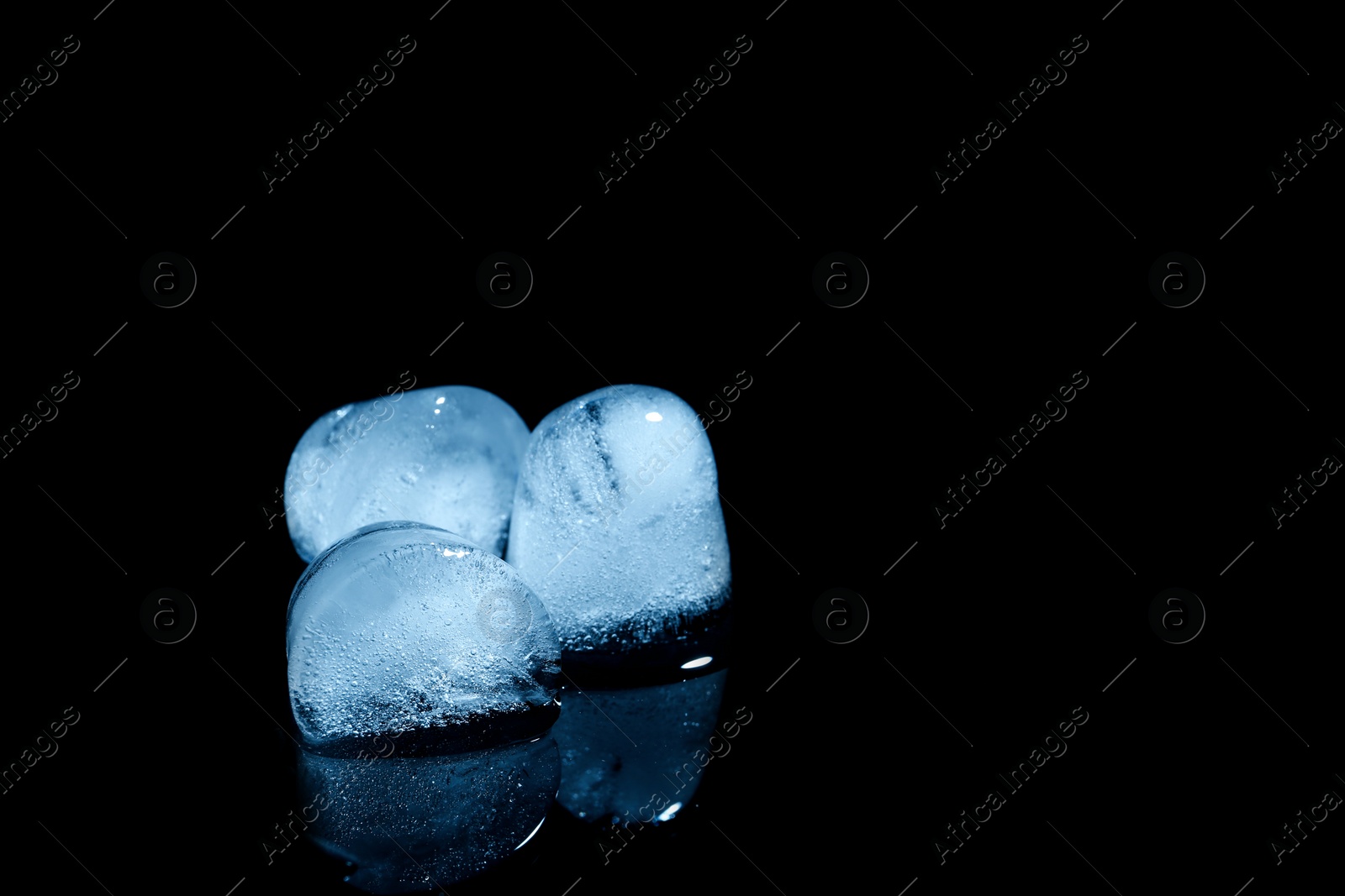 Photo of Melting ice cubes on black background. Space for text