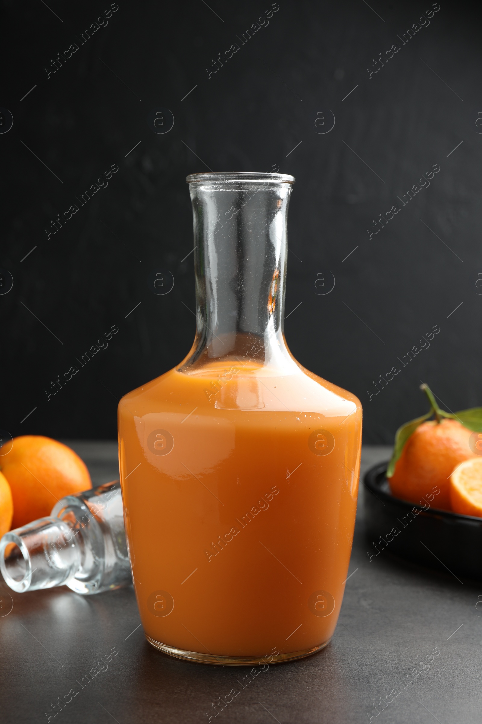 Photo of Delicious tangerine liqueur and fresh fruits on grey table