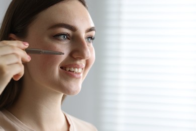 Photo of Smiling woman drawing freckles with pen indoors. Space for text
