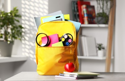 Yellow backpack and different school stationery on table indoors