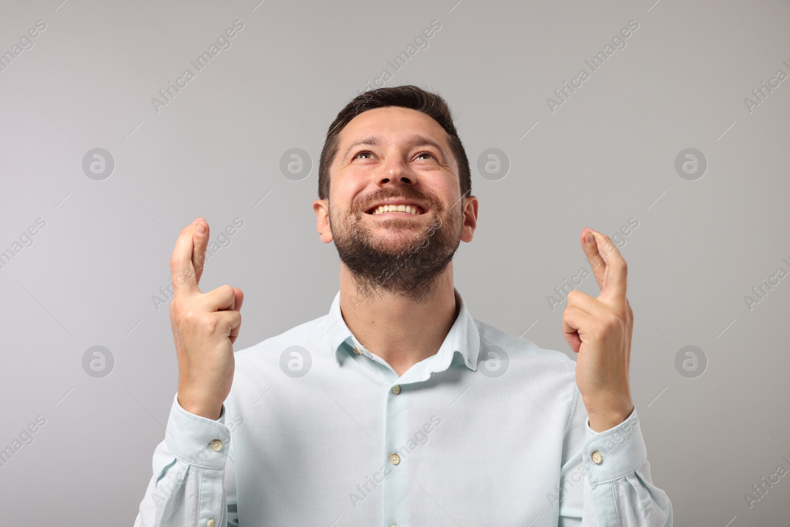 Photo of Happy man crossing his fingers on grey background