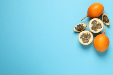 Photo of Delicious ripe granadillas on light blue background, flat lay. Space for text