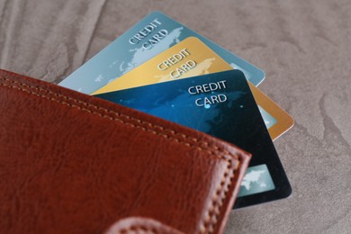 Photo of Credit cards and leather wallet on grey textured table, closeup