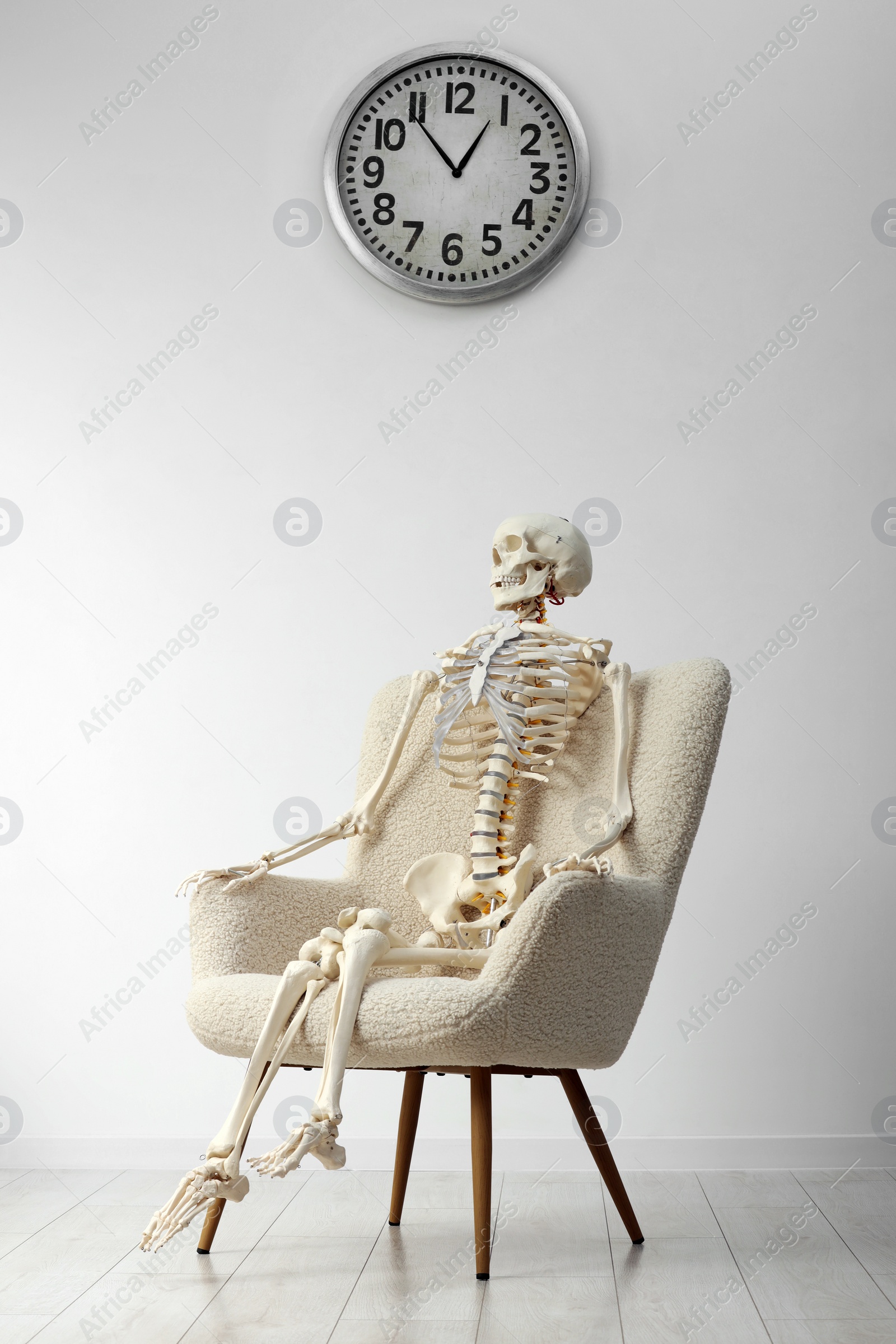 Photo of Waiting concept. Human skeleton sitting in armchair indoors