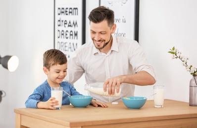 Father and son having breakfast with milk at table