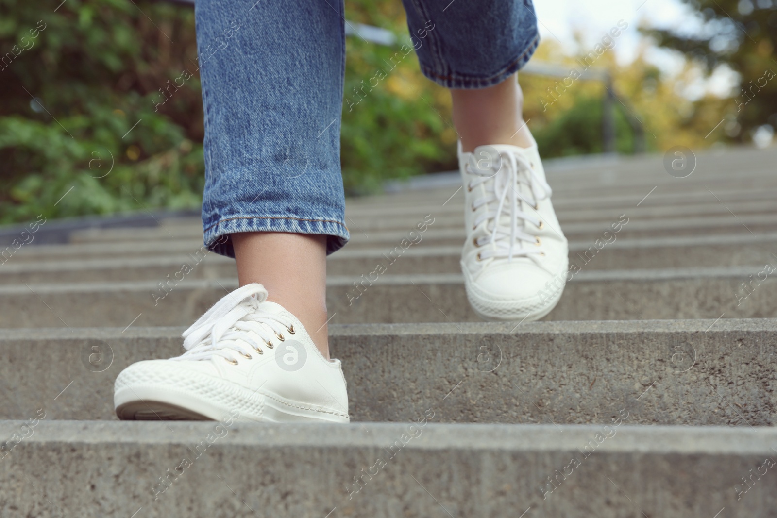 Photo of Woman in stylish black sneakers walking down stairs, closeup