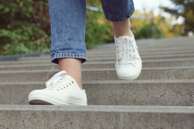 Woman in stylish black sneakers walking down stairs, closeup