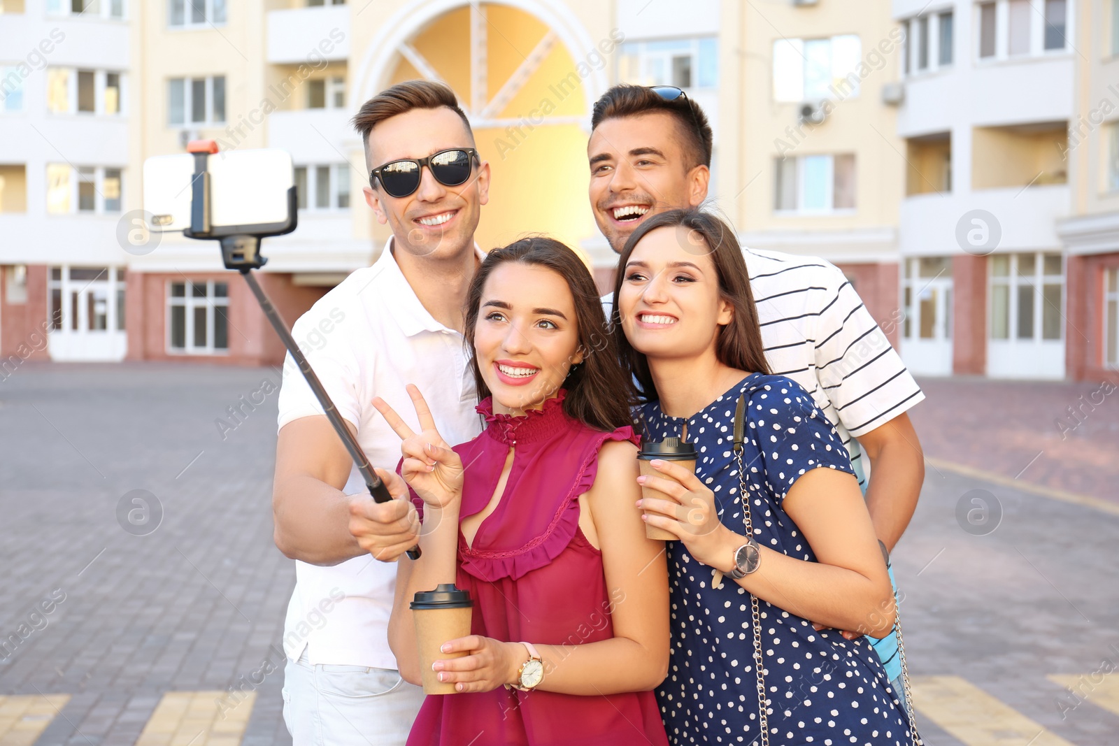 Photo of Group of young people taking selfie with monopod outdoors