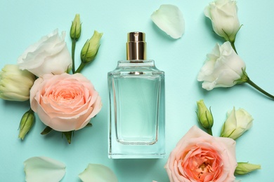 Photo of Flat lay composition with bottle of perfume and flowers on cyan background