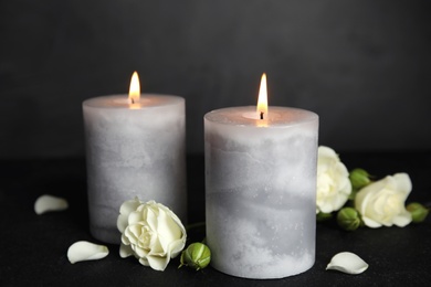 Photo of Burning candles and flowers on dark grey table