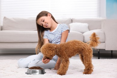 Little child feeding cute puppy on carpet at home. Lovely pet