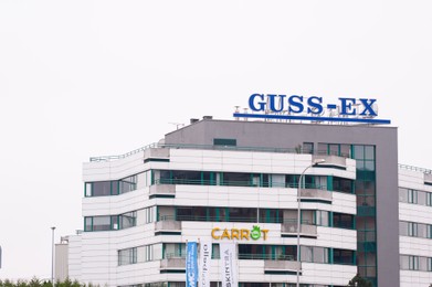 Photo of Warsaw, Poland - September 10, 2022: Building with modern Guss-Ex and Carrot logos