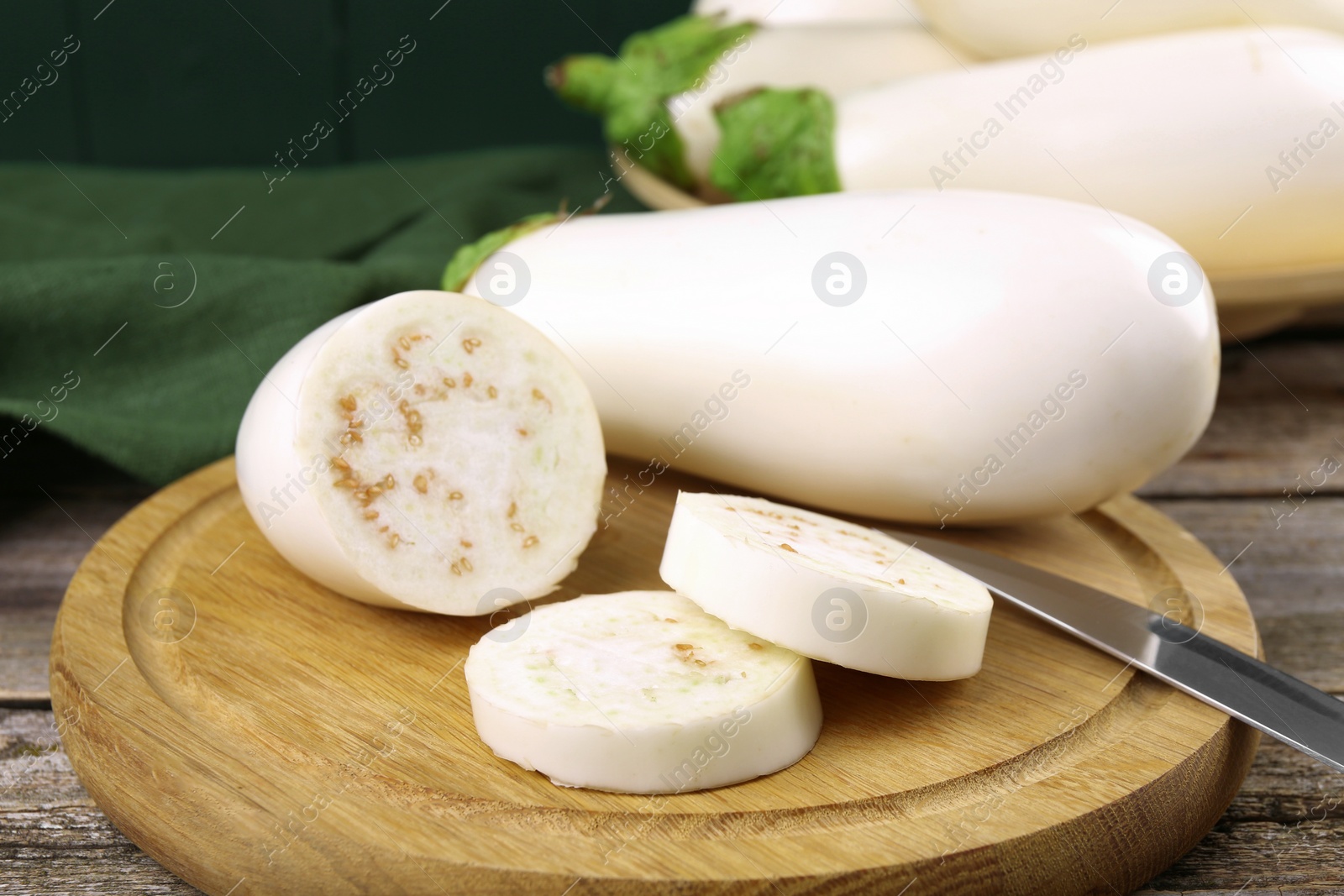 Photo of Board with raw eggplants and knife on wooden table