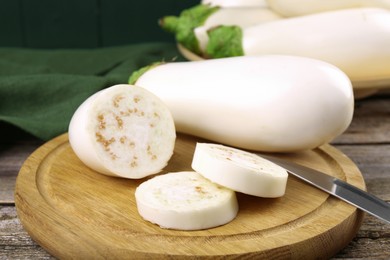 Photo of Board with raw eggplants and knife on wooden table