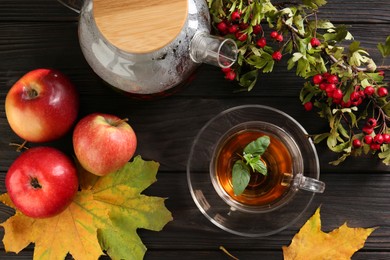 Photo of Hot tea, apples, dry leaves and viburnum on wooden table, flat lay. Autumn atmosphere