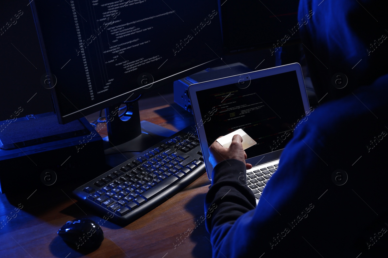Photo of Hacker with computers and credit card in dark room. Cyber crime