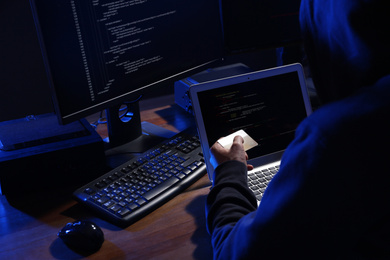 Hacker with computers and credit card in dark room. Cyber crime