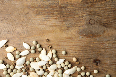 Mixed vegetable seeds on wooden background, flat lay. Space for text