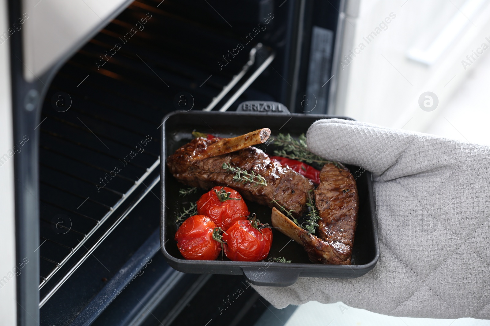 Photo of Chef taking delicious roasted ribs out of oven, closeup