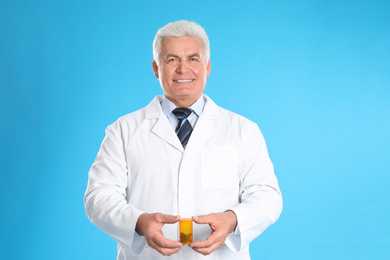 Senior pharmacist with pills on light blue background