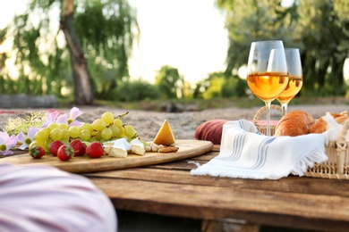 Food for picnic and white wine served on wooden pallet outdoors