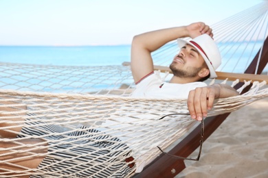 Young man resting in hammock at seaside. Summer vacation