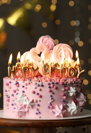 Photo of Beautiful birthday cake with burning candles on wooden stand