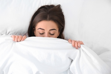 Photo of Young woman sleeping under blanket, top view. Bedtime