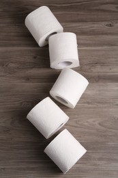 Photo of Soft toilet paper rolls on wooden table, flat lay