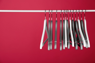 Photo of Empty clothes hangers on metal rail against color background. Space for text