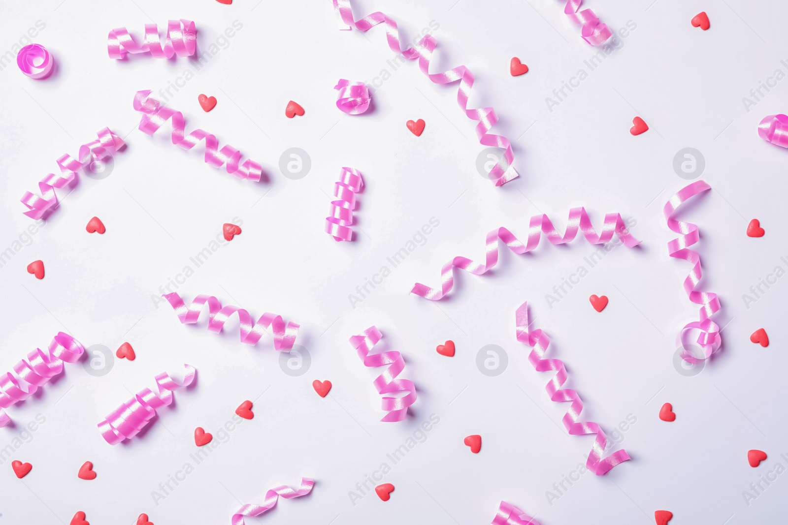 Photo of Pink serpentine streamers and heart shaped confetti on white background, top view