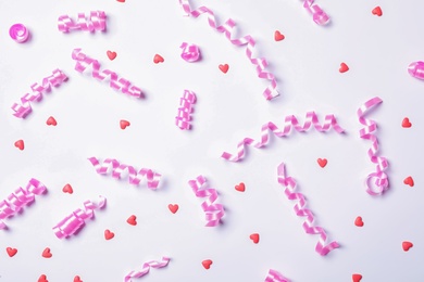 Photo of Pink serpentine streamers and heart shaped confetti on white background, top view