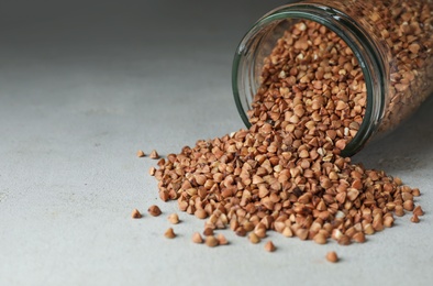 Photo of Uncooked organic buckwheat grains on light grey table. Space for text