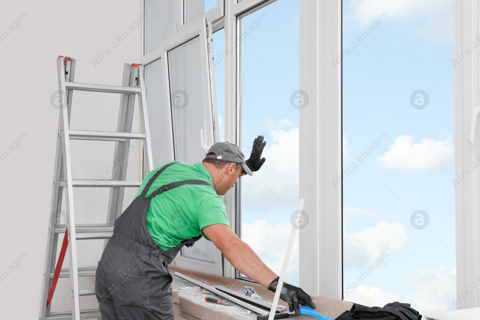 Photo of Worker in uniform installing double glazing window indoors