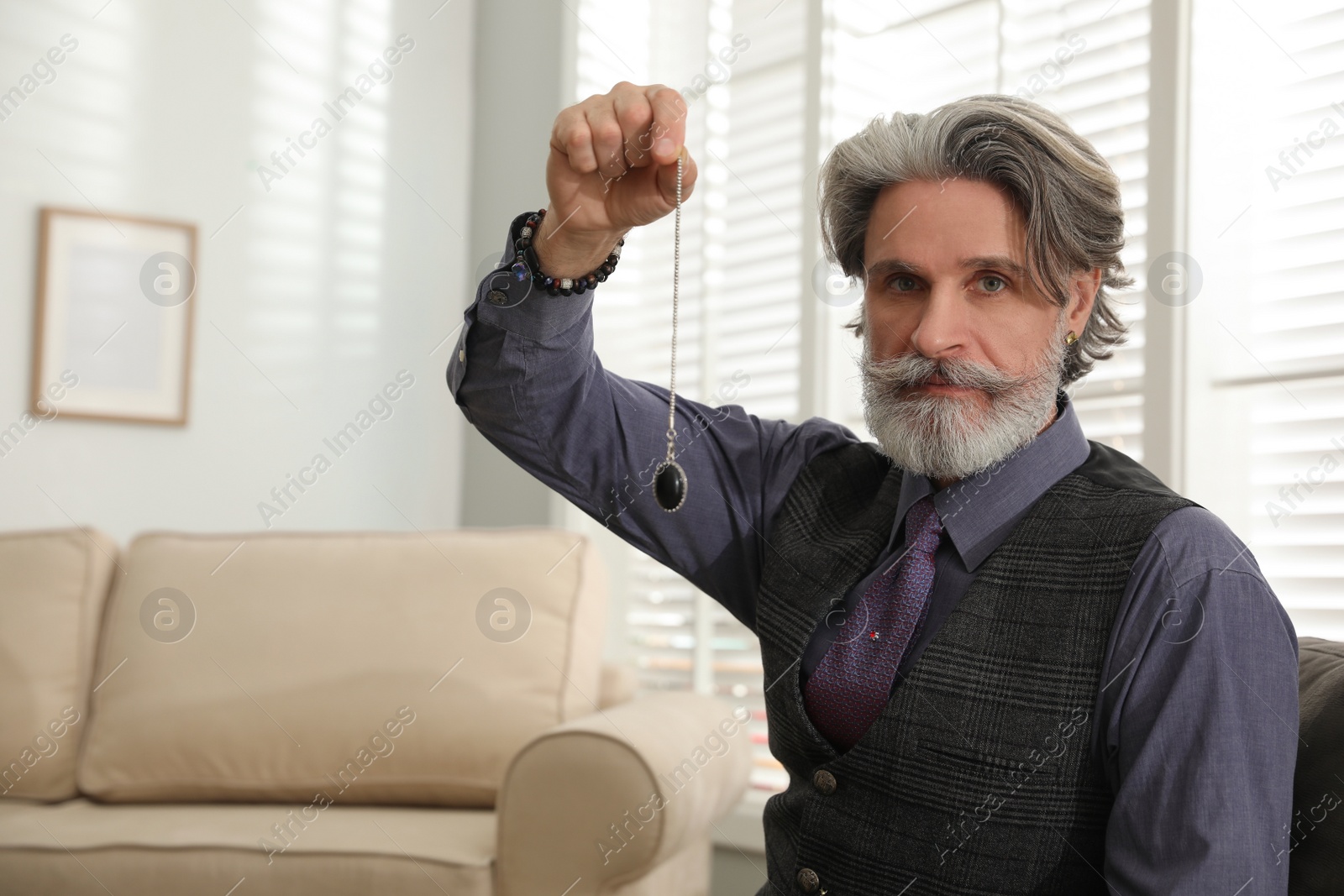 Photo of Psychotherapist with pendulum in office, space for text. Hypnotherapy session