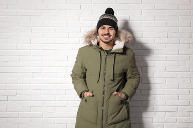 Photo of Young man wearing warm clothes against brick wall. Ready for winter vacation