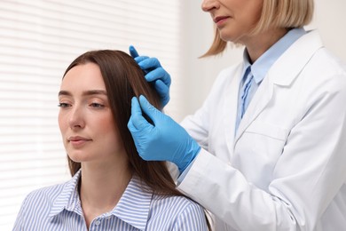 Photo of Trichologist examining patient`s hair in clinic, closeup