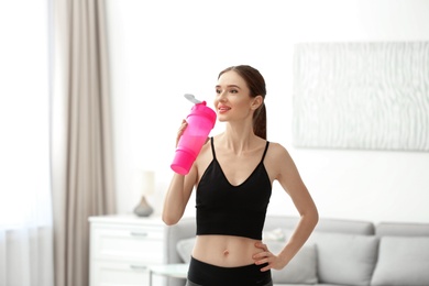 Athletic young woman drinking protein shake at home