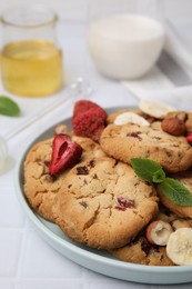 Photo of Cookies with freeze dried fruits, mint and nuts on white tiled table, closeup