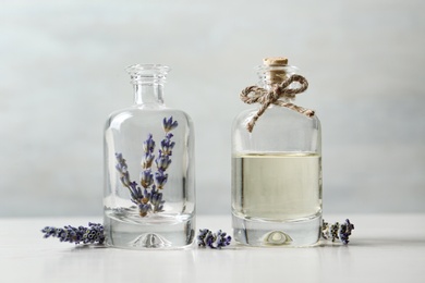 Bottles with natural essential oil and lavender flowers on white wooden table