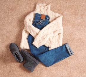 Flat lay composition with jeans, sweater and shoes on color fabric