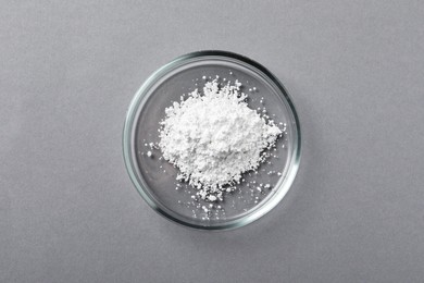 Photo of Petri dish with calcium carbonate powder on grey table, top view