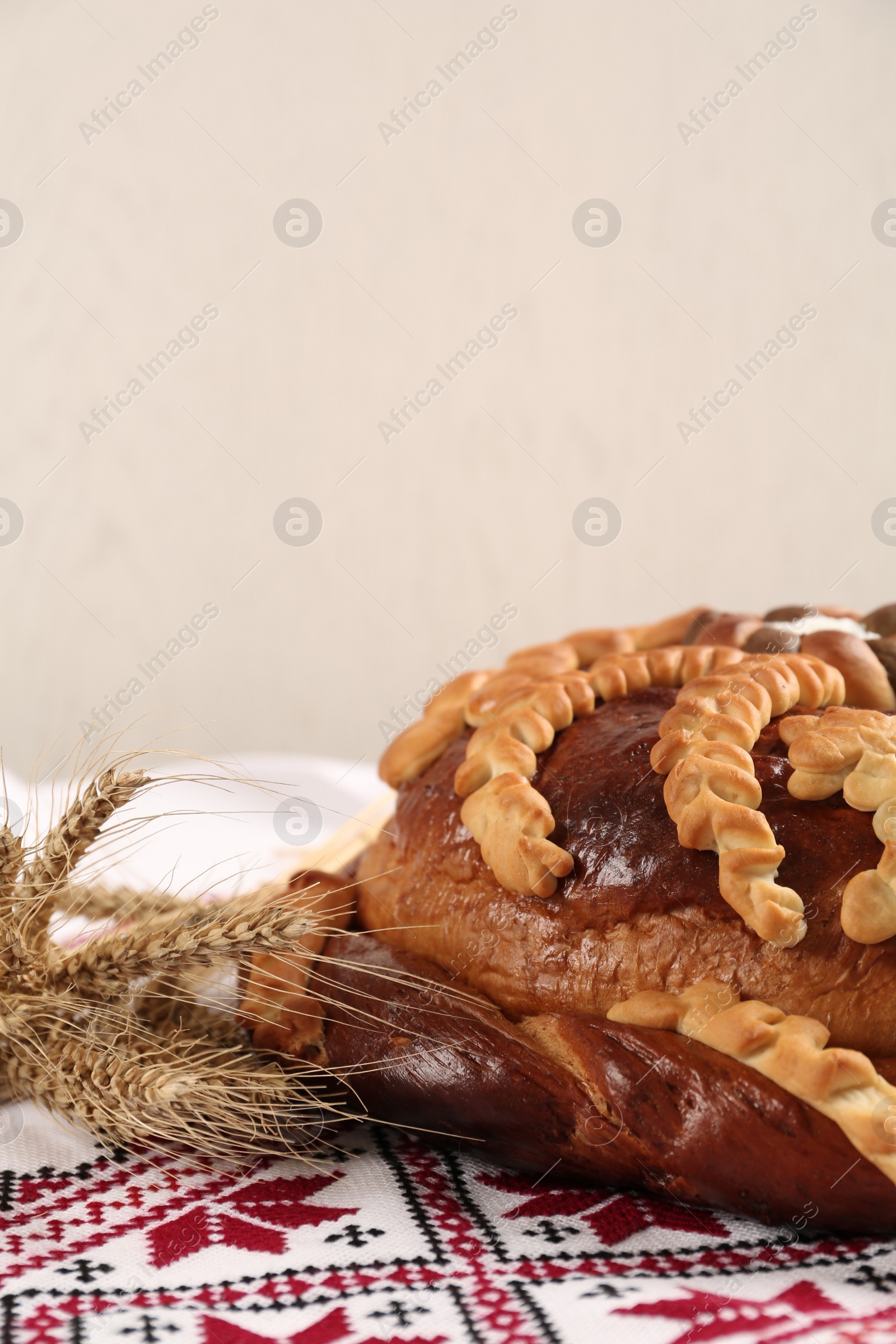 Photo of Rushnyk with korovai on light background, space for text. Ukrainian bread and salt welcoming tradition