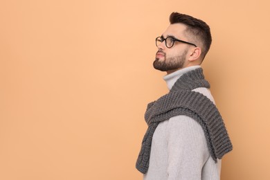 Handsome man in knitted scarf on beige background. Space for text